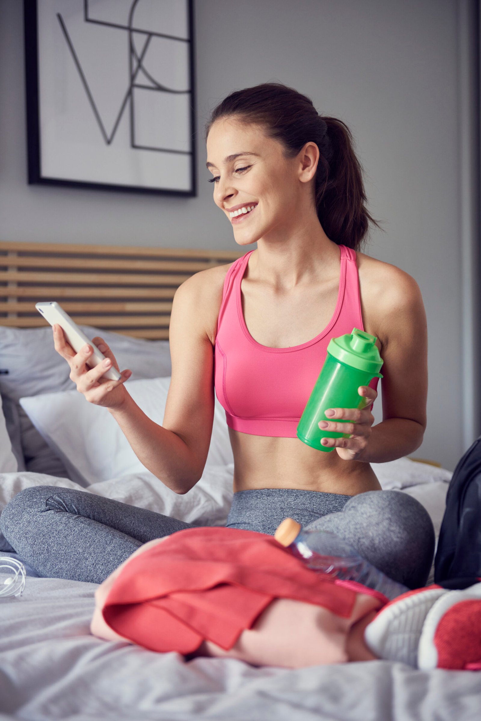 cheerful athlete using a mobile phone at bedroom