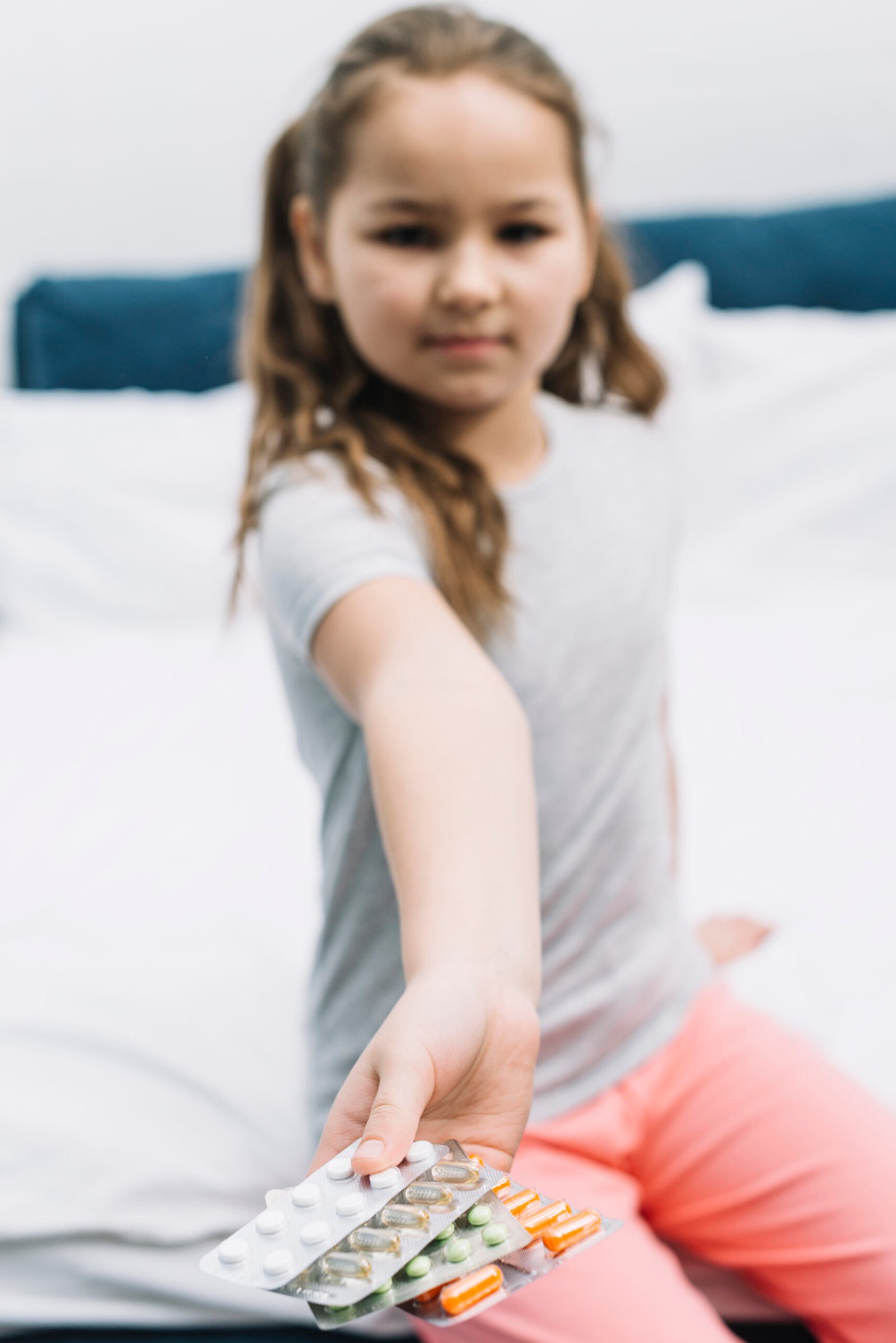 turva menina sentada na cama mostrando diferentes tipos de pilulas blister